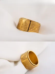 Macro detail of the rotatable gold stainless steel heart sutra ring with Buddhist carvings