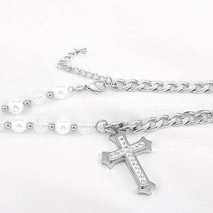 Collier punk en acier avec perles et pendentif croix en strass sur un tissu plissé blanc