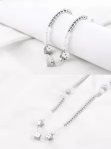 Détail du collier en acier titane avec perles à craquelures et pendentifs dés argentés