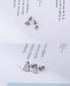 Detail of minimalist geometric triangle stud earrings with brushed stainless steel texture