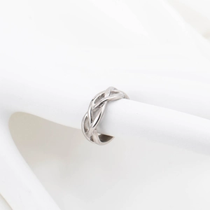 Minimalistischer silberner geflochtener Ring mit geometrischem Muster auf einem Podest