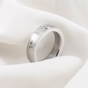 Brushed stainless steel ring with star-set crystals on white silk background
