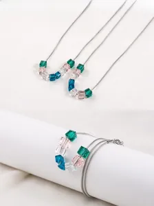 Détails de trois colliers avec pendentifs cubes en cristal sur chaînes serpent argentées