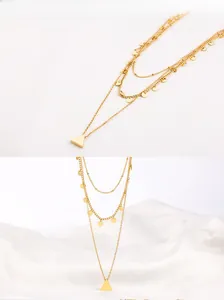 Detailed view of triple-layered gold-tone necklace with sequin charms and triangle pendant