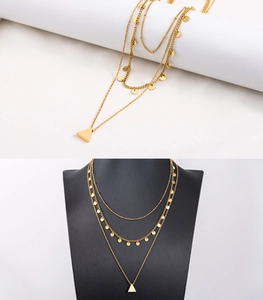 Detail of triple-layer gold necklace featuring circular sequins and a polished triangle pendant