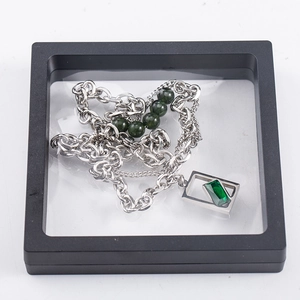 Collar con gema verde en caja de exhibición con película de PE transparente