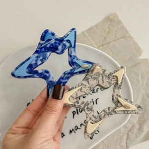 Set of two hollow star-shaped acetate hair claws in blue and beige marble texture
