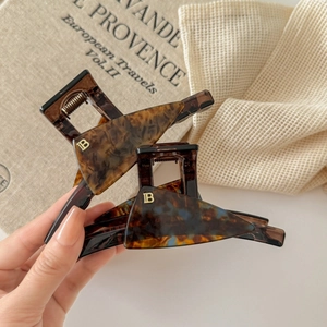French style acetate claw clips set with gold metal B logo on marbled finish