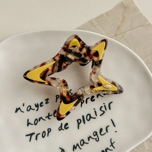 Close-up of tortoise shell hollow star hair claw clip with yellow triangle accents