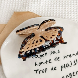Detail view of double-layered butterfly hair claw with tortoiseshell pattern and gold logo