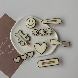 Ensemble de barrettes minimalistes crème et noir avec smileys et nœuds sur plateau
