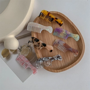 Mini comb hair clips in tortoise shell and marble patterns on wooden tray