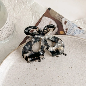 Elegant butterfly hair claw clip with black and white acetate marble texture in a tray
