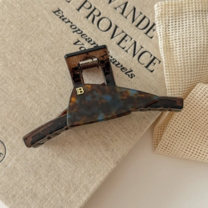 Close-up of amber tortoiseshell claw clip featuring a metallic gold letter B detail