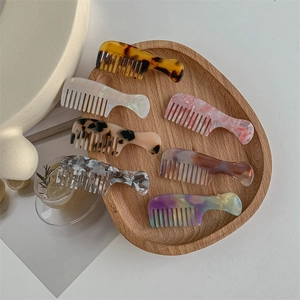 Minimalist acetate comb-shaped hair clips in various colors on a wooden tray