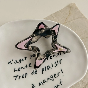 Detail of star-shaped hair claw with grey marble texture and pink moon-shaped accents