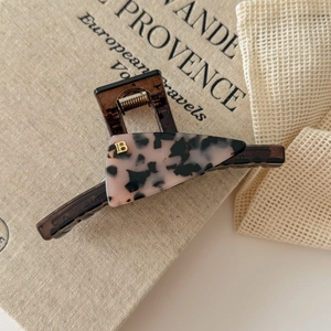 Close-up of brown and pink tortoiseshell acetate hair claw clip with golden B logo