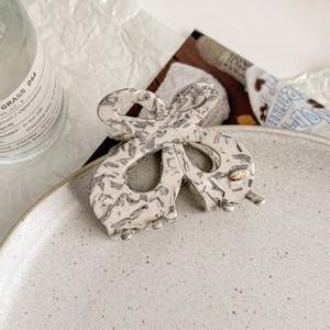Detail of a beige butterfly hair claw clip with black marble texture on a ceramic plate