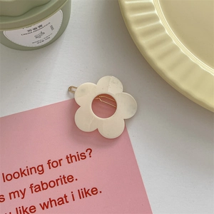 Close-up of cream-white resin flower hair clip with a gold metal barrette back