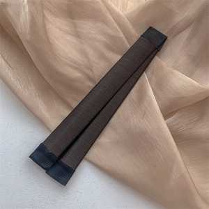 Gros plan de deux accessoires chignon en cheveux synthétiques brun foncé sur tissu doux