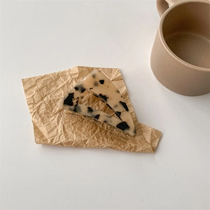 Dettaglio molletta per capelli triangolare tartarugata su carta vintage stropicciata