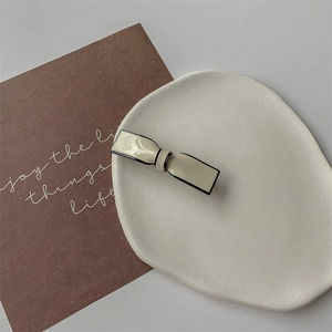 Détail d'une pince à cheveux rectangulaire crème minimaliste avec une bordure noire