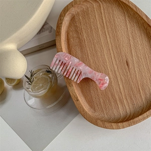 Detailed close-up of pink marble pattern acetate mini comb hair clip on a wooden tray