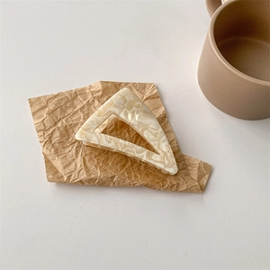 Vista dettagliata di una pinza per capelli a triangolo in acetato marmorizzato crema