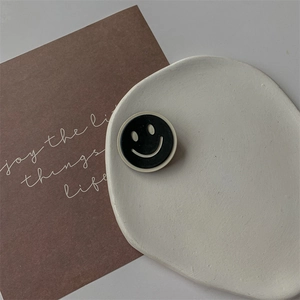 Support de téléphone noir et blanc avec smiley sur un plateau en céramique blanche