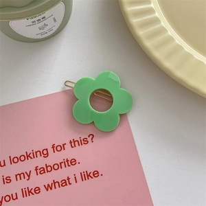 Detail of green flower hair clip with a golden metal pin on a macaron color background