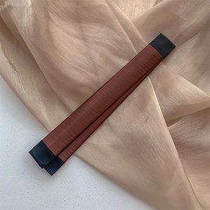 Détail d'un chignon magique en soie marron rouge avec embouts noirs sur tissu délicat