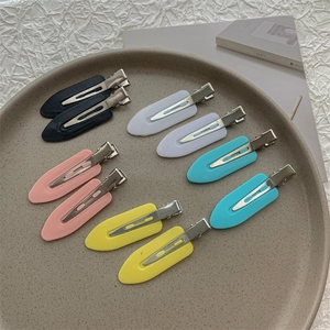 Set of colorful seamless hair clips for styling arranged on a ceramic tray with a book