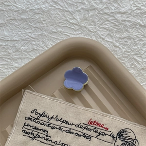 Gros plan détaillé d'une mini pince à cheveux fleurie violette et crème sur un plateau
