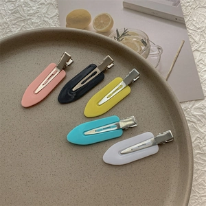 Flat lay of colorful resin seamless hair clips on a ceramic plate for daily styling