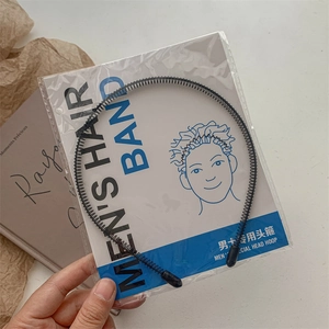 Detail of a wavy black metal men's hair band in transparent packaging with insert card