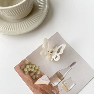 Detail view of pearlescent butterfly hair claw clip with metallic spring mechanism