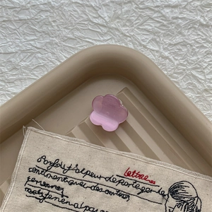 Gros plan sur une mini pince à cheveux en acétate violette en forme de fleur sur plateau