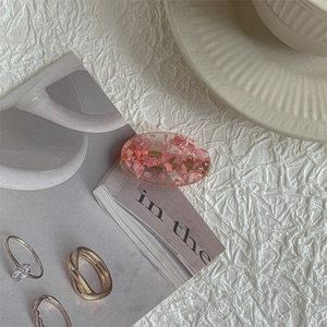 Detail of pink oval acrylic hair clip with embedded shell flakes and gold rings