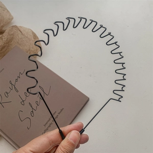 Detail of black wavy metal headband with anti-slip teeth over French vintage book