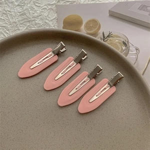 Set of four pink matte hair clips on a grey tray for daily fringe styling and fixing