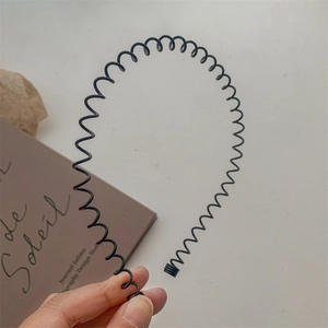 Close-up of black wavy metal headband with flexible spiral structure and protective tips