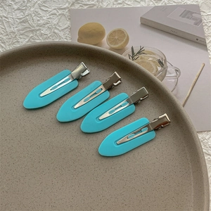 Close-up of four light blue creaseless hair clips set on a decorative ceramic plate
