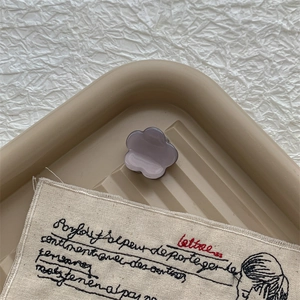 Gros plan d'une mini pince à cheveux en forme de fleur violette en acétate sur un plateau
