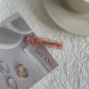 Detail of pink cherry blossom resin hair clip with gold glitter on white aesthetic background