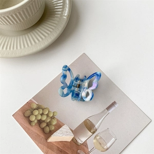Detailed macro shot of blue marble butterfly hair claw clip on aesthetic card background