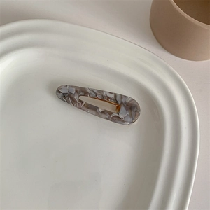 Macro detail of teardrop hair clip featuring a vintage marble texture in grey and brown