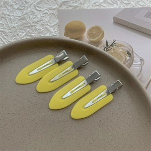 Set of four matte yellow duckbill hair clips neatly arranged on a ceramic tray detail