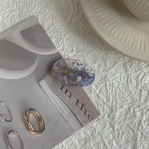 Detail of oval resin hair clip with purple glitter and elegant metallic stacking rings