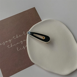 Gros plan d'une pince à cheveux contrastée noir et blanc sur une assiette blanche décorée