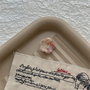 Gros plan d'une pince à cheveux fleur en acétate marbré rose sur plateau décoratif